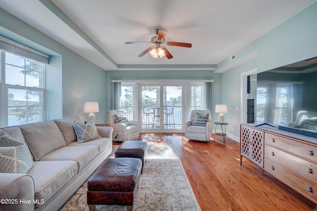 living area featuring a ceiling fan, baseboards, visible vents, light wood-style floors, and french doors