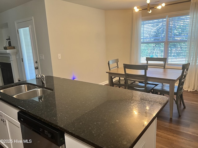 kitchen featuring stainless steel dishwasher, dark stone counters, sink, and white cabinets