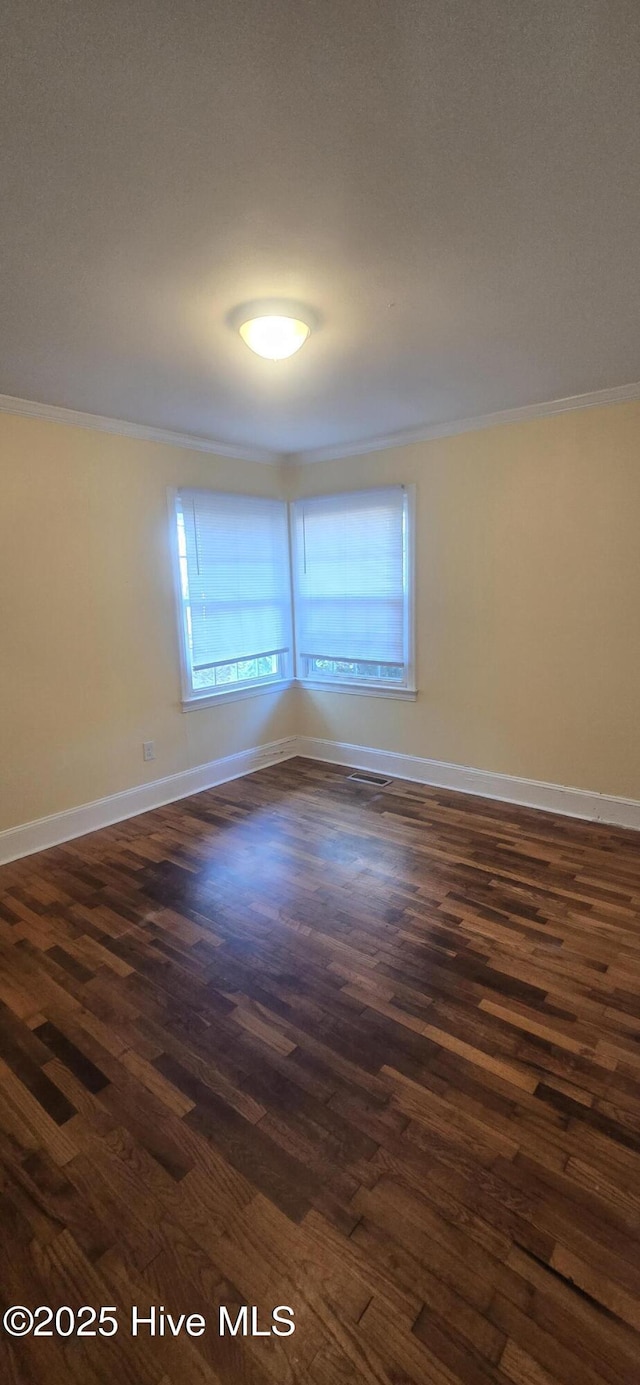 empty room with ornamental molding, dark wood-type flooring, and baseboards