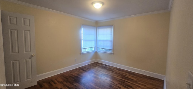 empty room featuring dark wood-style floors, visible vents, baseboards, and ornamental molding