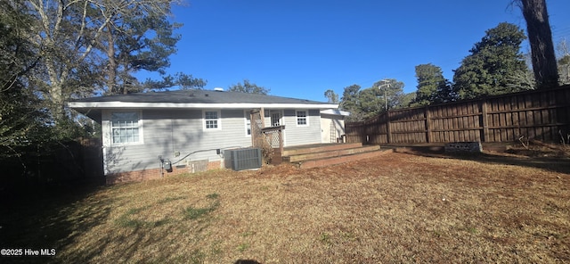 rear view of house featuring crawl space, fence, central AC unit, and a yard