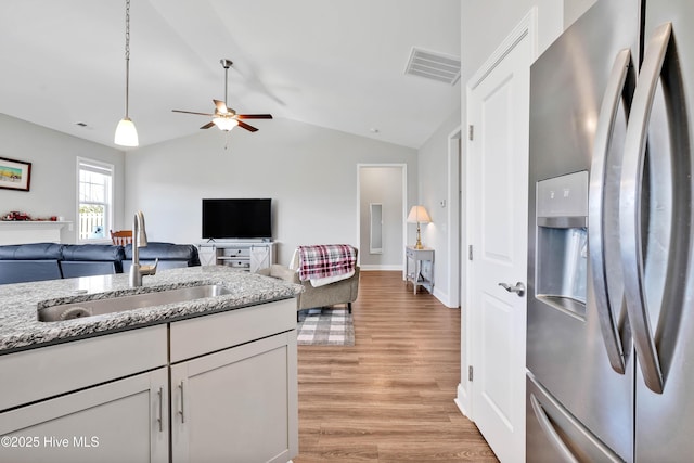 kitchen with sink, vaulted ceiling, stainless steel fridge with ice dispenser, light hardwood / wood-style flooring, and ceiling fan