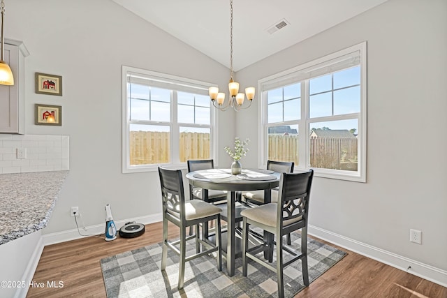 dining area featuring a chandelier, vaulted ceiling, and hardwood / wood-style floors