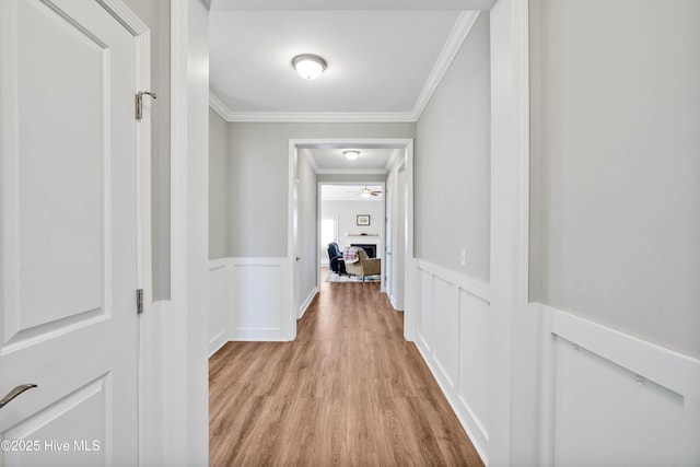 hallway with crown molding and light hardwood / wood-style floors