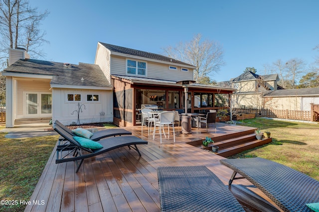 rear view of house featuring a deck and a lawn