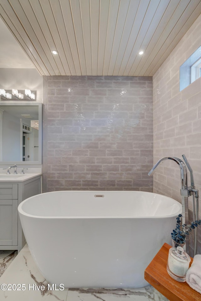 bathroom featuring wood ceiling, vanity, a bathtub, and tile walls