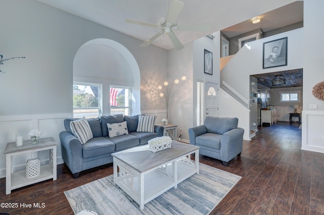 living room with dark hardwood / wood-style flooring, a towering ceiling, plenty of natural light, and ceiling fan