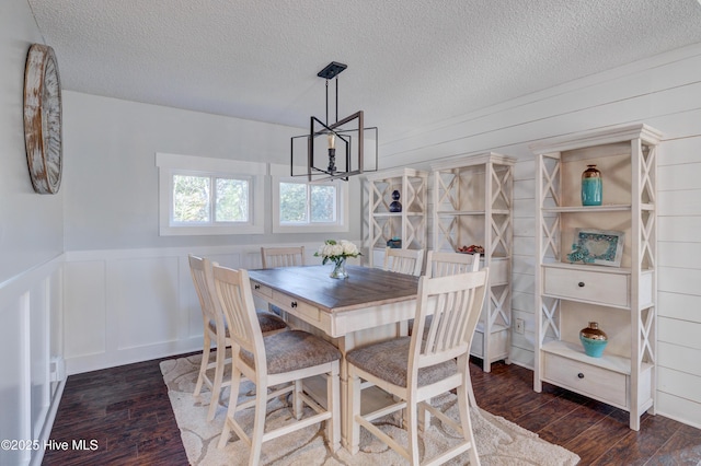 dining area featuring dark hardwood / wood-style floors, a textured ceiling, and a notable chandelier