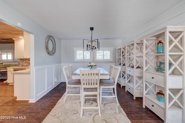 dining room featuring dark wood-type flooring, plenty of natural light, a chandelier, and a textured ceiling