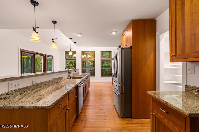 kitchen with sink, decorative light fixtures, light hardwood / wood-style flooring, stainless steel appliances, and light stone countertops