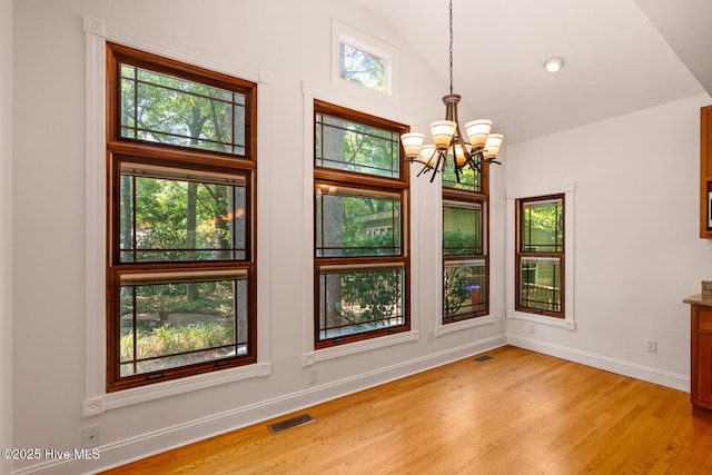 unfurnished dining area featuring light hardwood / wood-style flooring, a notable chandelier, and vaulted ceiling