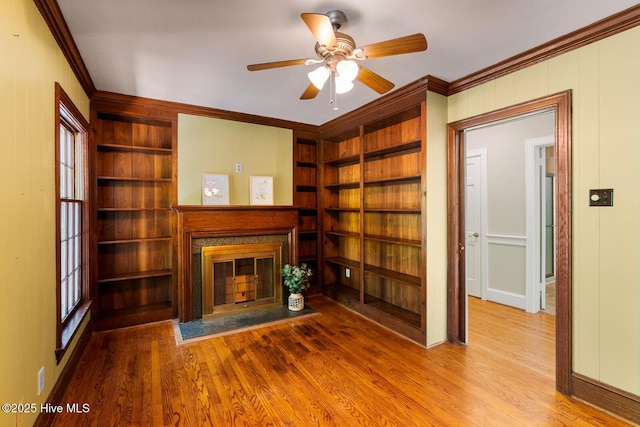 unfurnished living room with wood-type flooring, crown molding, and built in shelves