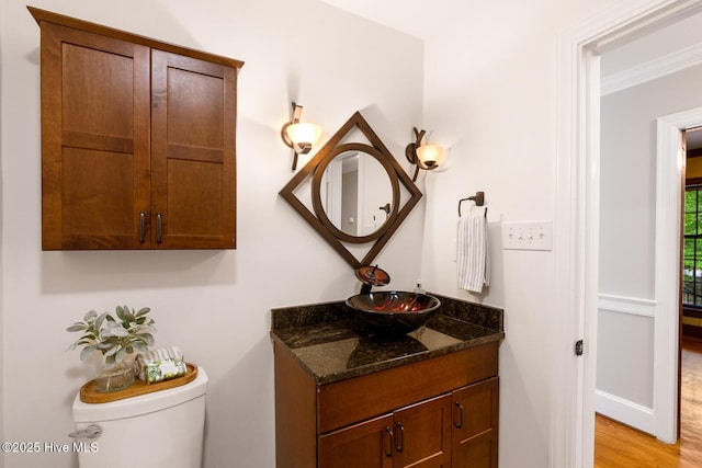 bathroom with ornamental molding, vanity, toilet, and wood-type flooring