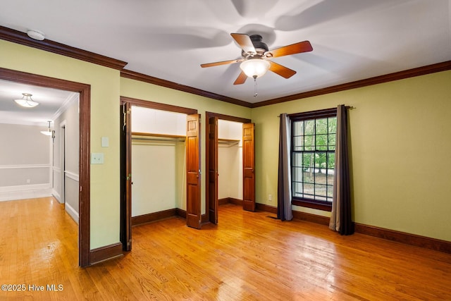 unfurnished bedroom featuring crown molding, two closets, light hardwood / wood-style floors, and ceiling fan