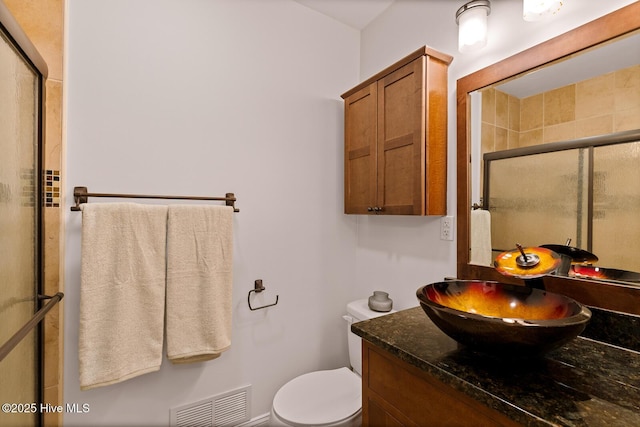 bathroom with a shower with door, vanity, and toilet