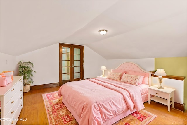 bedroom with lofted ceiling, light hardwood / wood-style floors, and french doors