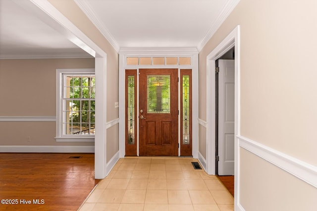 foyer with ornamental molding and light tile patterned floors