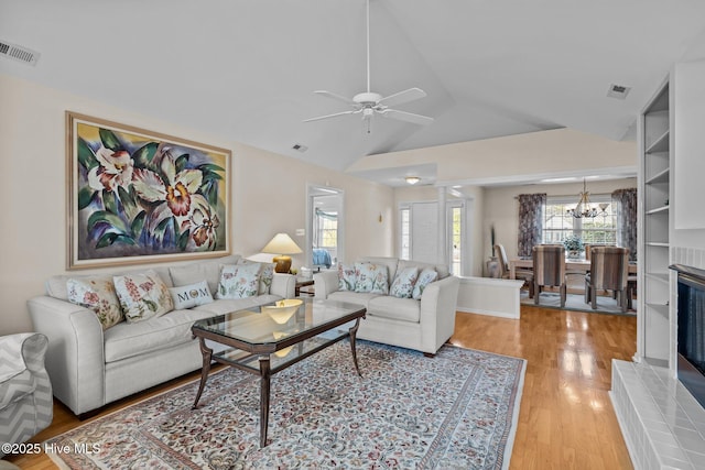 living room with wood-type flooring, vaulted ceiling, and ceiling fan with notable chandelier