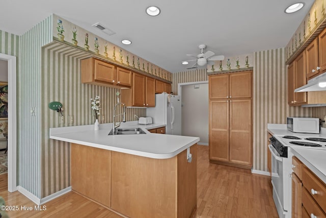 kitchen featuring white appliances, kitchen peninsula, sink, and light wood-type flooring