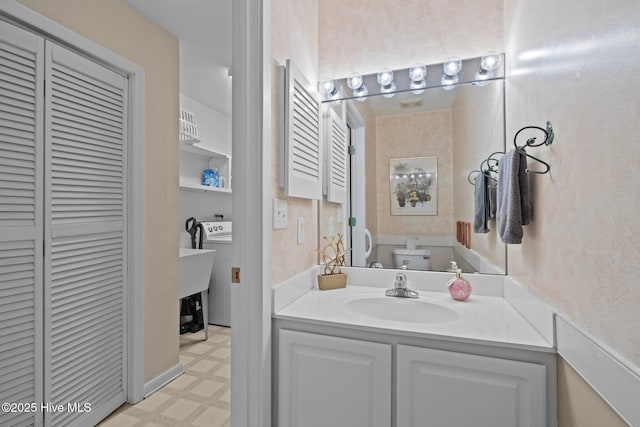 bathroom featuring vanity, toilet, and washer / clothes dryer