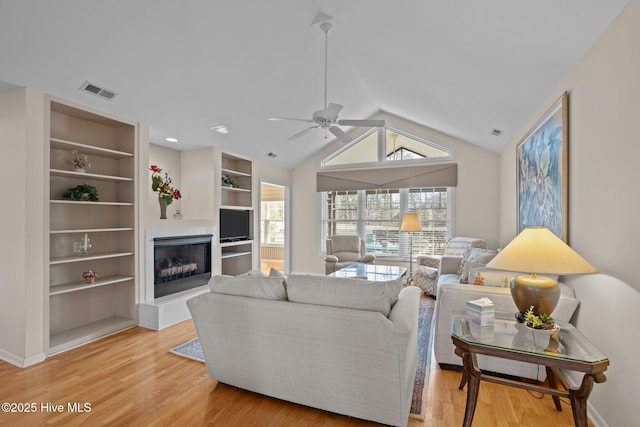 living room with hardwood / wood-style flooring, ceiling fan, lofted ceiling, and built in shelves