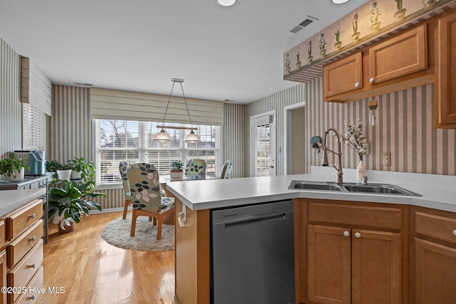 kitchen featuring hanging light fixtures, black dishwasher, sink, and light hardwood / wood-style flooring