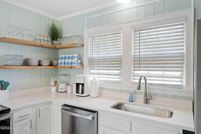 kitchen featuring sink, ornamental molding, wooden walls, dishwasher, and white cabinets