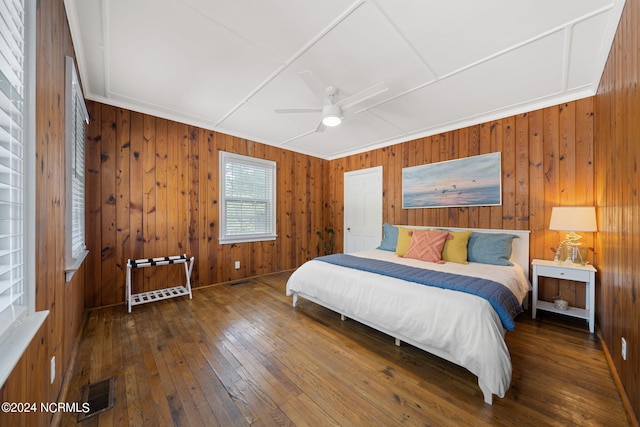 bedroom with wooden walls, ceiling fan, and dark hardwood / wood-style floors