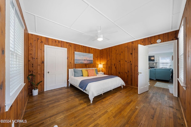 bedroom with multiple windows, a fireplace, dark hardwood / wood-style floors, and ceiling fan