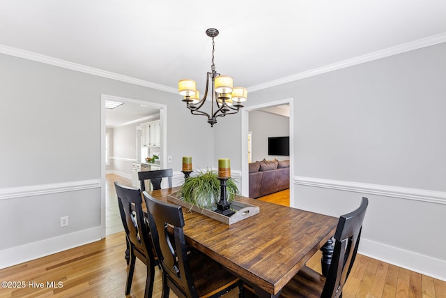 dining area with crown molding, an inviting chandelier, and light hardwood / wood-style floors