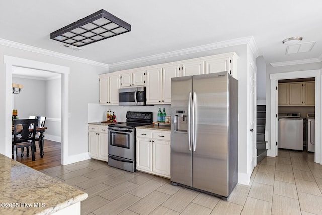 kitchen with white cabinetry, ornamental molding, washer and clothes dryer, and stainless steel appliances