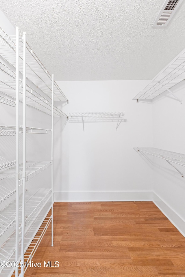 walk in closet with hardwood / wood-style floors