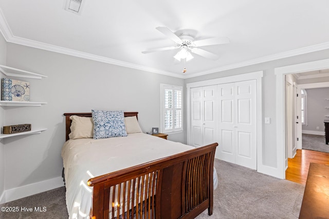 carpeted bedroom with ornamental molding, a closet, and ceiling fan