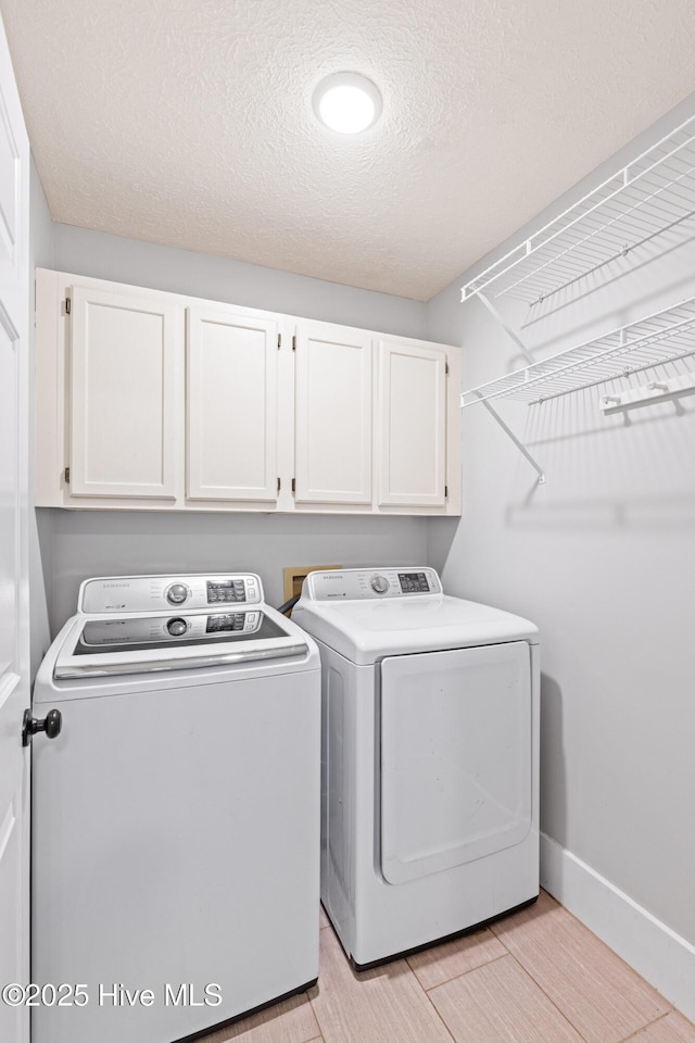 laundry area featuring cabinets, washer and clothes dryer, and a textured ceiling