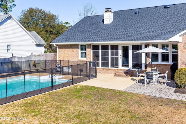 back of house featuring a fenced in pool, a patio, a sunroom, and a lawn