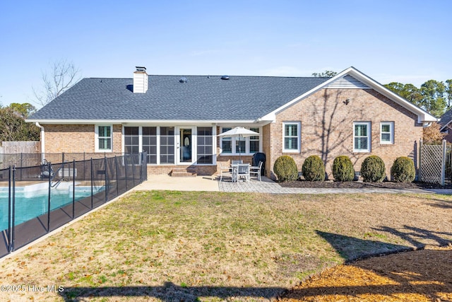 back of property with a fenced in pool, a yard, and a patio