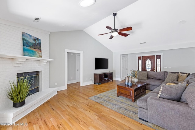 living room featuring ceiling fan, wood-type flooring, a fireplace, and high vaulted ceiling