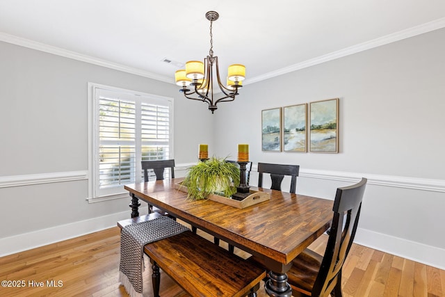 dining space featuring ornamental molding, light hardwood / wood-style flooring, and a notable chandelier