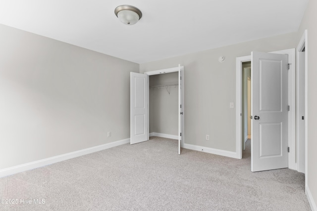 unfurnished bedroom with light colored carpet and a closet