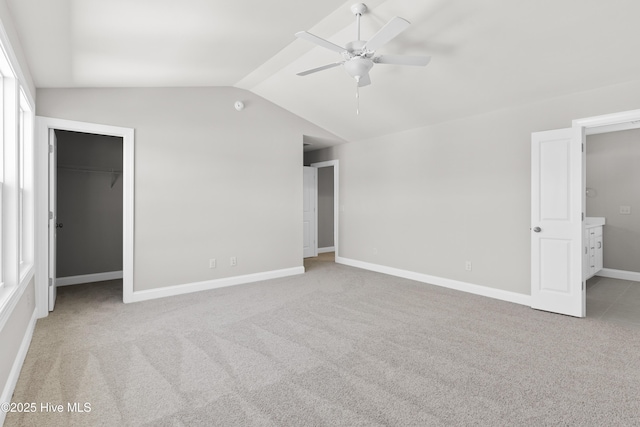 unfurnished bedroom featuring lofted ceiling, ceiling fan, a spacious closet, light colored carpet, and a closet