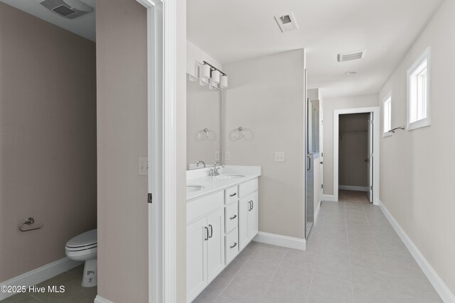 bathroom featuring a shower with door, vanity, tile patterned flooring, and toilet