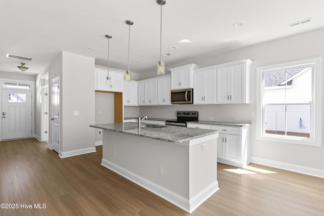 kitchen featuring sink, stone counters, white cabinetry, appliances with stainless steel finishes, and a center island with sink