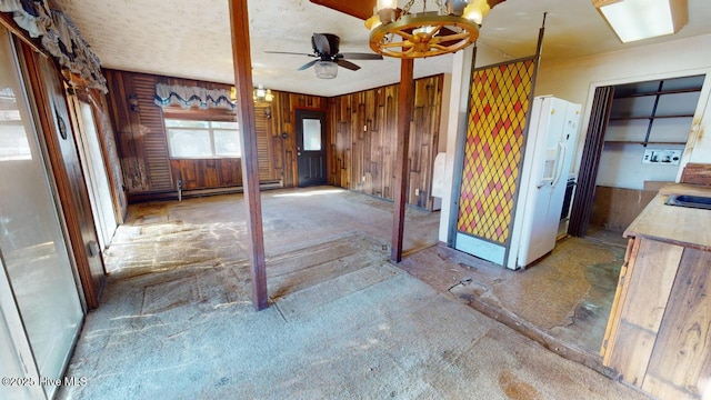 kitchen featuring ceiling fan, white refrigerator with ice dispenser, sink, and wood walls