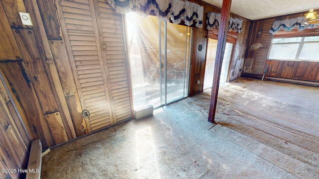 empty room with a baseboard heating unit and wood walls