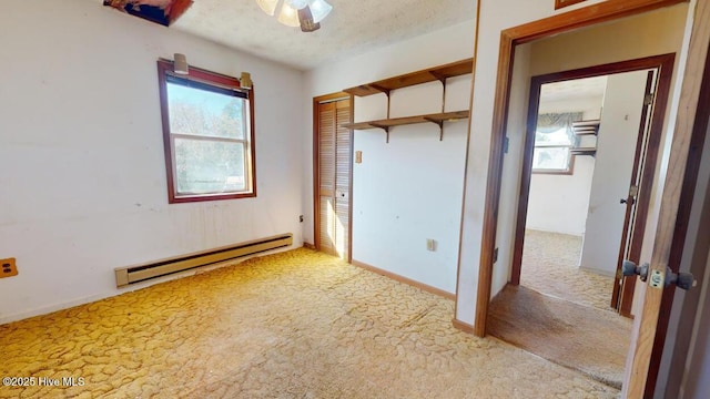 unfurnished bedroom with a baseboard heating unit, light colored carpet, a textured ceiling, and a closet