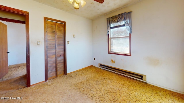 unfurnished bedroom featuring a textured ceiling, a baseboard radiator, ceiling fan, and carpet