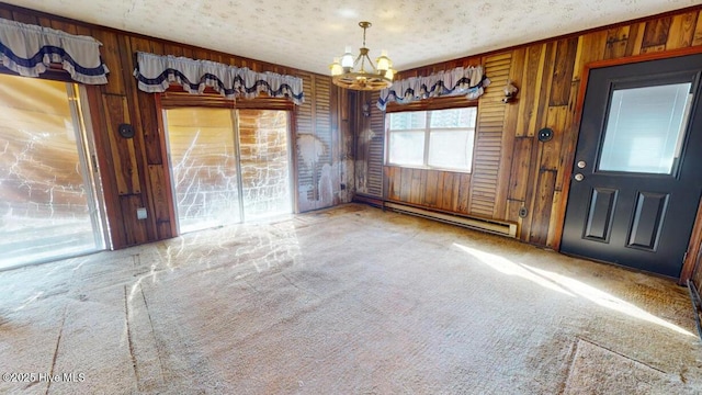 interior space with a baseboard heating unit, light colored carpet, a textured ceiling, and wood walls