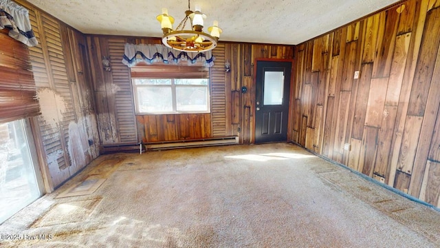 empty room with wooden walls, carpet flooring, a baseboard heating unit, a notable chandelier, and a textured ceiling