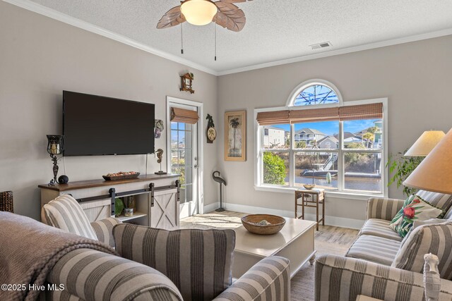 living room with ceiling fan, ornamental molding, light hardwood / wood-style floors, and a textured ceiling