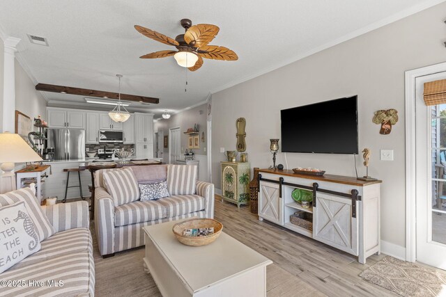 living room with ornamental molding, ceiling fan, a textured ceiling, and light wood-type flooring